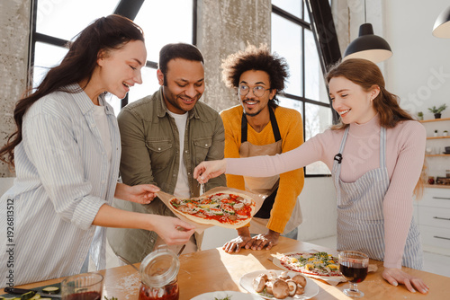Foto Group of smiling, happy multiracial friends making pizza, dinner in modern kitch