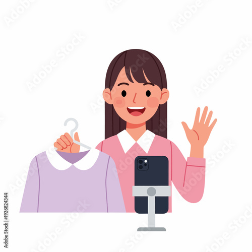 Smiling young woman live streaming fashion content, holding a purple dress on a hanger while waving to her audience.