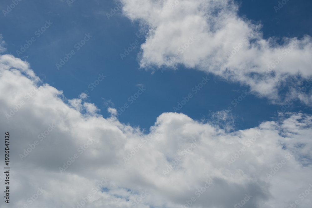 Fototapeta premium White and grey clouds scattered across a bright blue sky