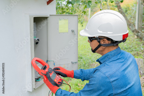 Foto Professional electrician using a clamp meter to measure the flow of electric cur