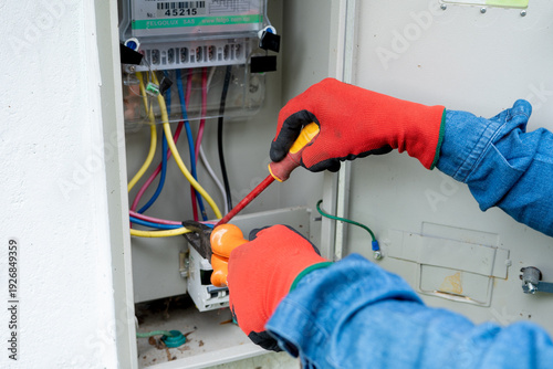 Obraz na płótnie Close-up of an electrician's hands using pliers and a screwdriver to install and