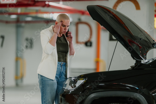 Billede på lærred Woman standing next to a broken down car with an open hood in an underground par