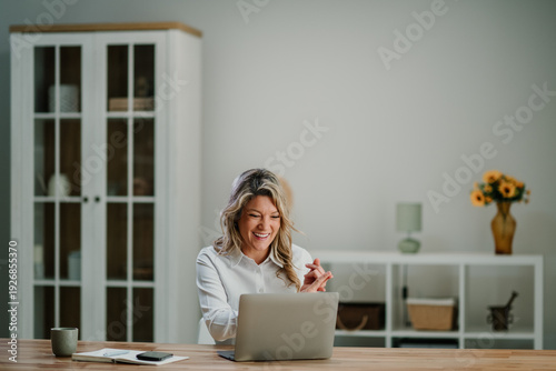 Wallpaper Mural Woman smiling and laughing during video call or online meeting using a laptop at home office desk, working remotely Torontodigital.ca
