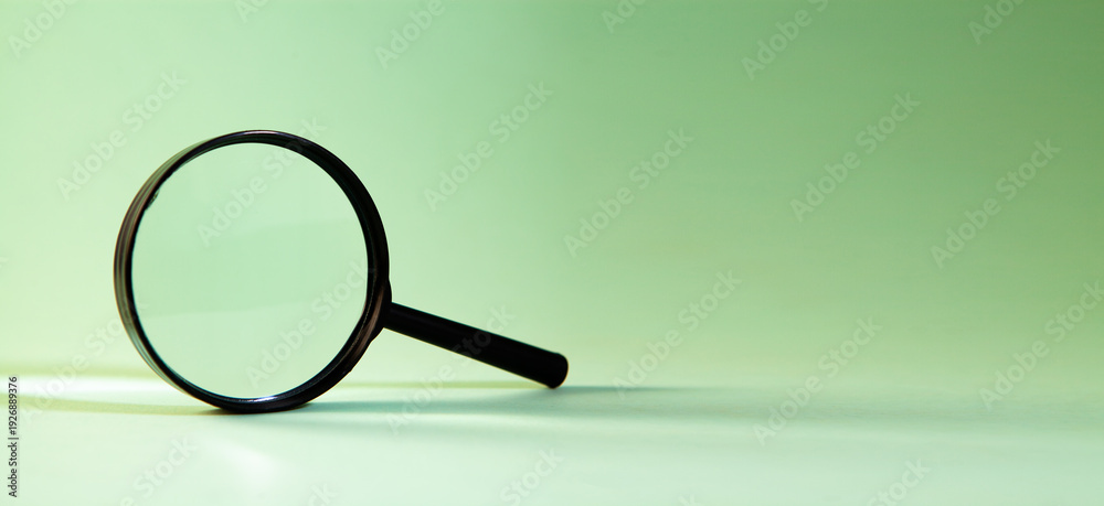 Fototapeta premium Magnifying glass on a green background.