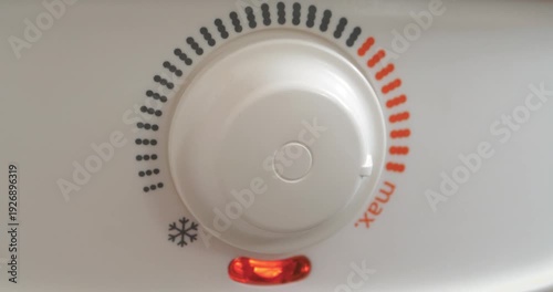 Regulator for heating water in home boiler. Man turns temperature control on heater of water. Red light indicator comes off, boiler has turned off. Boiler heats water from cold water supply system
