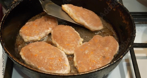 Meat cutlets are fried in a frying pan. A cook turns the cutlets over in frying pan. Cooking, frying meat. Five meat patties are cooked on boiling oil in a pan. Fat unhealthy food with carcinogens
