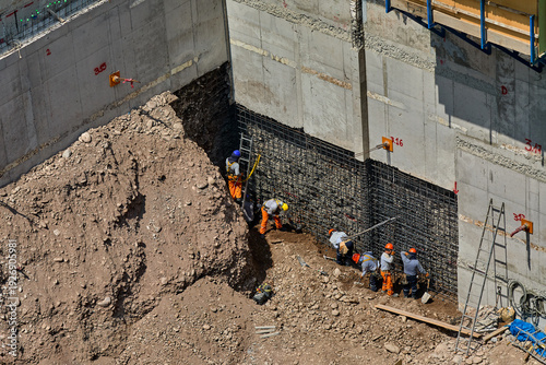 Construction workers installing structural reinforcement at a building site, demonstrating safety procedures, professional working standards, and best practices in modern real estate development and u