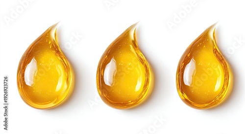 Three droplets of golden liquid, possibly oil, glistening against a white background
