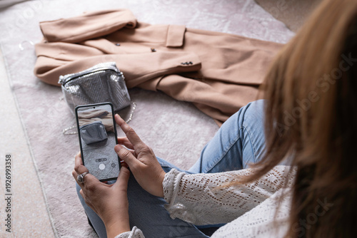 Φωτογραφία An anonymous woman taking photos of secondhand clothes with her mobile phone to