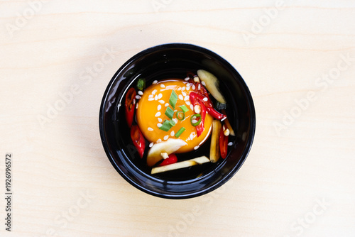Foto Pickled egg yolk in soy sauce topped with sesame seeds, chili, and garlic in a black bowl, a popular Asian side dish or topping for rice