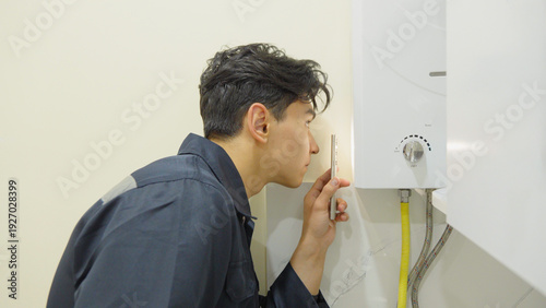 Fotografia Man inspecting gas water heater in home kitchen