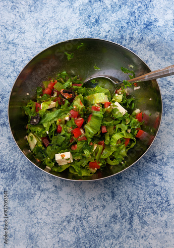 Raw Salad of Fresh Iceberg Lettuce with Tomatoes, Olives, White Salad Cheese, Garlic and Olive Oil.