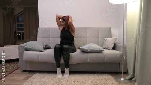 A woman sits on a sofa and turns her head