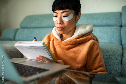 Woman with under eye patches planning at home with laptop