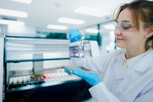 Fotografie Histotechnologist inspecting stained tissue slides in metal rack after automated h&e staining process