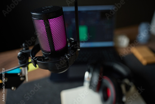 Wallpaper Mural Illuminated studio microphone on boom arm on desk with headphones and laptop with audio editing timeline in background. Concept of podcast recording, streaming setup and audio content creation Torontodigital.ca