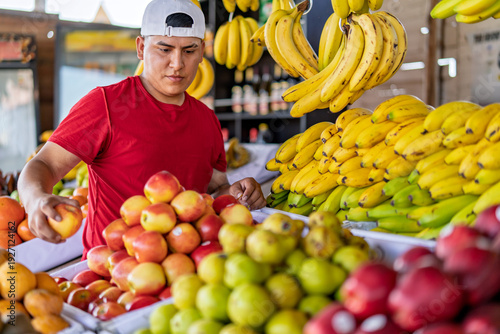 Bilde på lerret Young man arranging fresh fruit at market stall