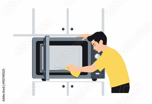 Young Adult Cleaning a Kitchen Microwave with a Cloth as Part of Daily Household Maintenance and Hygiene Routine