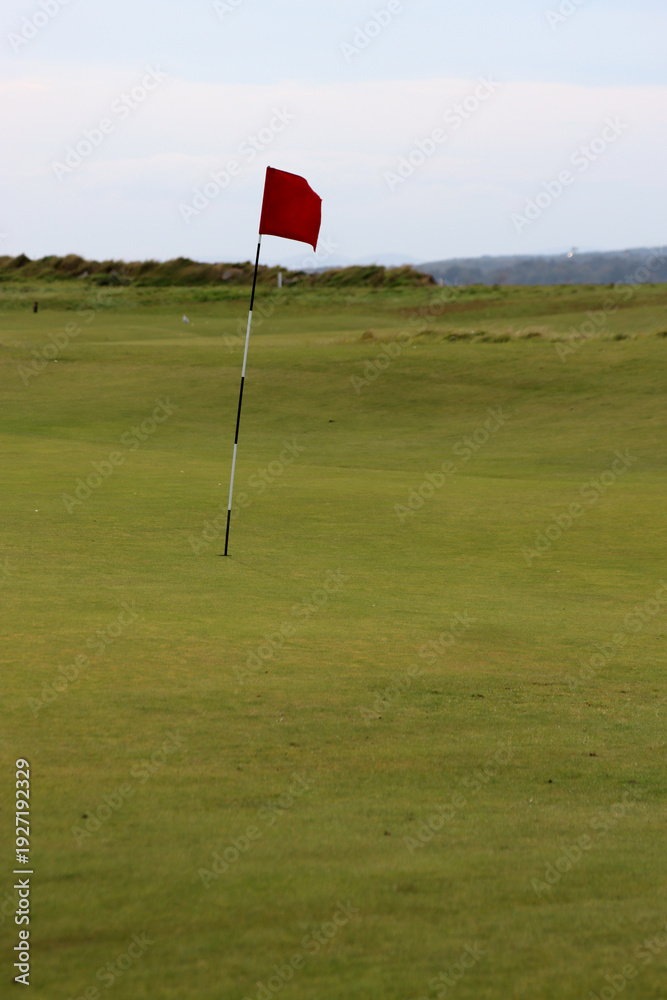 Obraz premium red flag on golf course marking hole