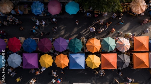 Market stalls with colorful umbrellas and visitors walking on a busy street