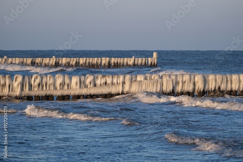 rows of wooden breakwaters covered with ice  by Baltic Sea in Uniescie, Mielno. Western Pomerania, Poland  
