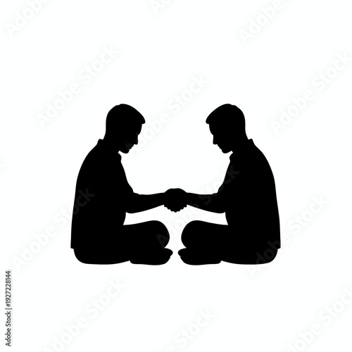 Solid black silhouettes of men sitting cross legged on the ground and shaking hands for a respectful greeting or traditional reconciliation isolated on white background