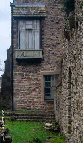 An old stone building with a balcony and large windows. An old English cottage with a balcony