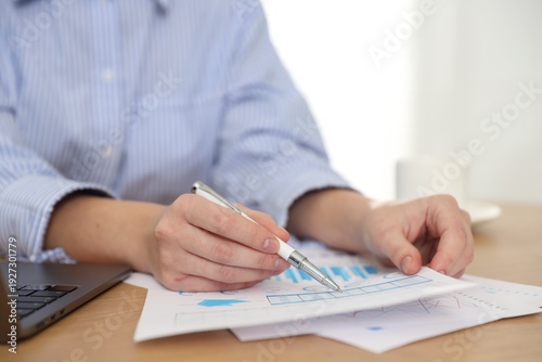 Secretary with pen doing paperwork at table in office, closeup