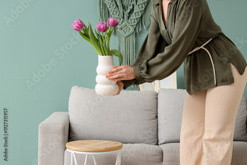 Young woman putting vase wi...