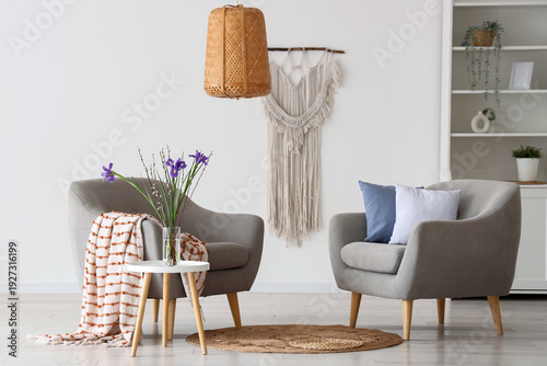 Interior of light living room with armchairs and spring flowers
