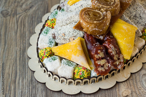 Various Turkish Delights and candies are presented in a stylish wooden plate at wooden surface
