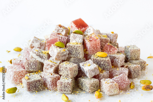Traditional Turkish Delights are designed with pistachios on a white surface.