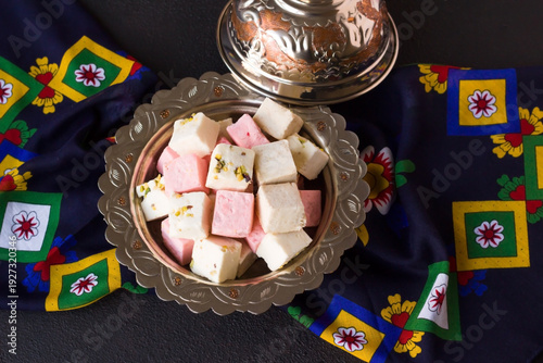 Red rose flavored and pistachio Turkish pulled halva,designed in a rustic silver bowl on dark surface