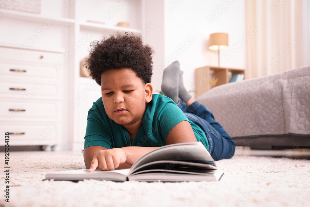 Fototapeta premium Boy reading book on floor at home