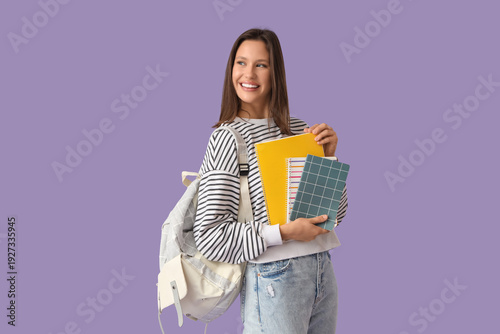 Female student with notebooks on lilac background