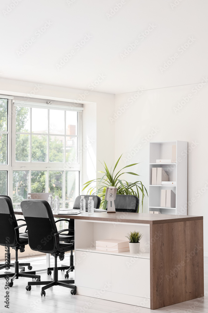 Fototapeta premium Interior of conference hall with desk, shelf unit and palm plant
