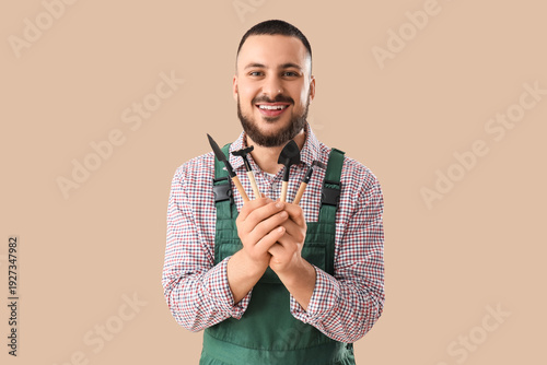 Male gardener with tools on beige background