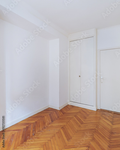 Empty bright room with herringbone wooden floor in renovated apartment.