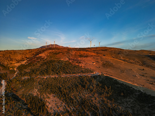 4K Aerial panorama of a large wind farm on a mountain plateau near Mostar, Bosnia and Herzegovina. Industrial landscape with multiple wind turbines at golden sunset.