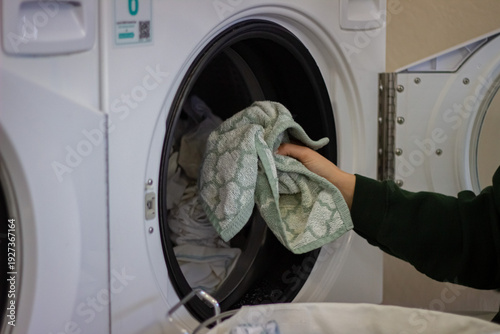 Wallpaper Mural Female hand loading towel into washing machine in self service laundromat Torontodigital.ca