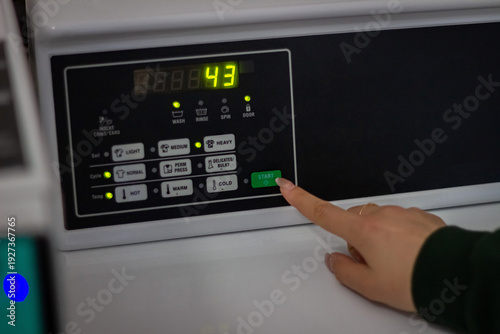 Wallpaper Mural Female hand pressing start button on washing machine control panel Torontodigital.ca