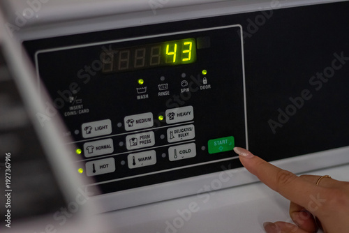 Wallpaper Mural Female hand pressing start button on washing machine panel close up Torontodigital.ca