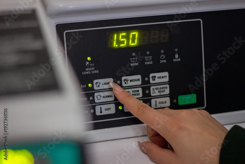 Wallpaper Mural Female hand selecting wash cycle on washing machine control panel Torontodigital.ca
