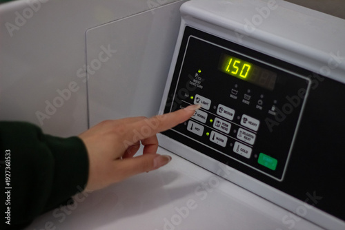 Wallpaper Mural Female hand selecting soil level on washing machine control panel Torontodigital.ca