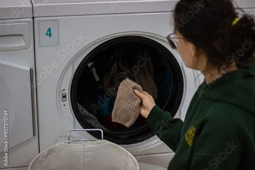 Wallpaper Mural Woman putting sock into washing machine in self service laundromat Torontodigital.ca