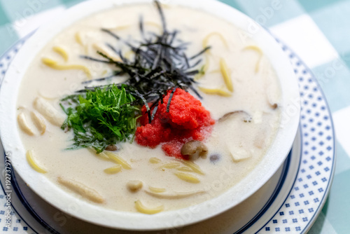 明太子、大葉、刻み海苔を添え、クリーミーな和風ホワイトソースにパスタを合わせた一皿。明太子のつぶつぶ感と薬味のアクセント、和洋折衷の優しい味わいを伝えるランチやディナーメニューの販促・広告用素材に。 | A Mentaiko (cod roe) and white sauce pasta topped with Shiso leaves and shredded Nori seaweed.