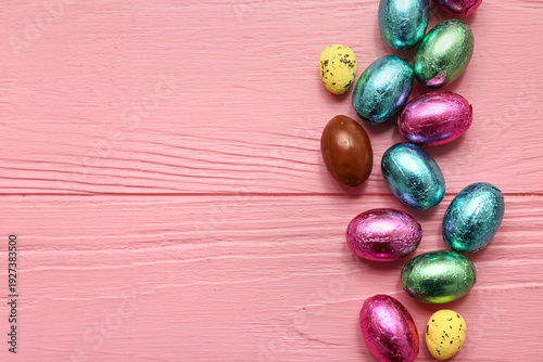 Chocolate Easter eggs in foil on pink wooden background