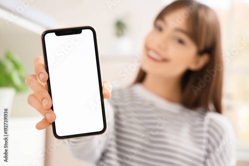Young woman with blank mobile phone in kitchen, closeup