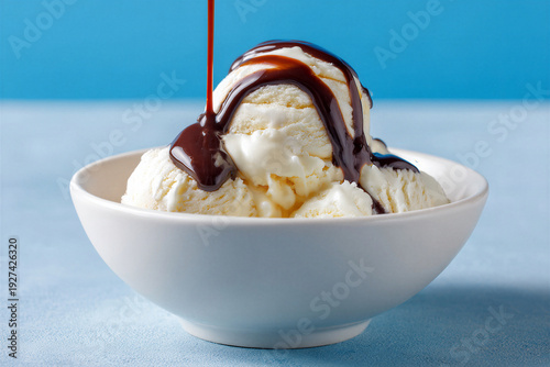 Vanilla ice cream with chocolate syrup in white bowl on blue background
