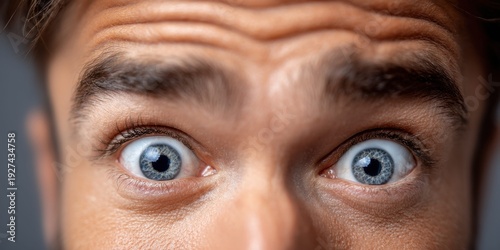 Close-up extreme shot of a man's wide, surprised blue eyes and furrowed brow